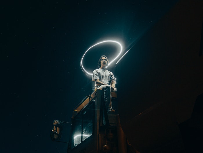 Man sitting on a truck with a halo in light graffiti above his head