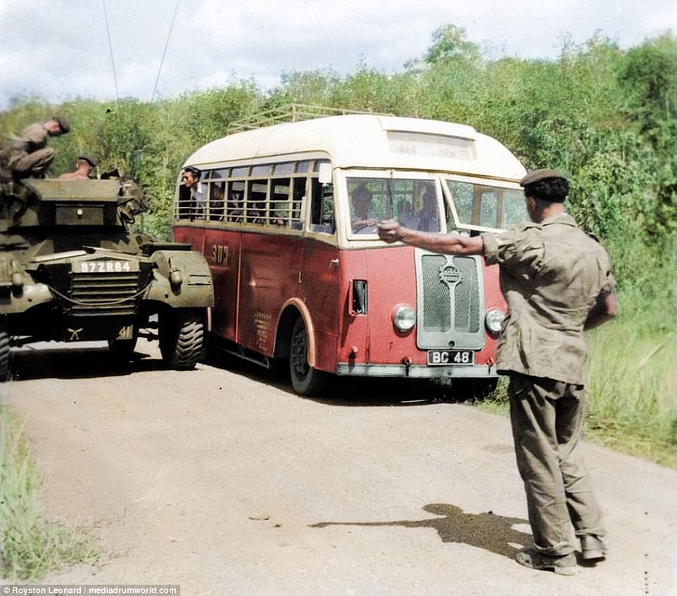 A soldier directs a bus, which has pulled up alongside a tank. The conflict was labelled as an