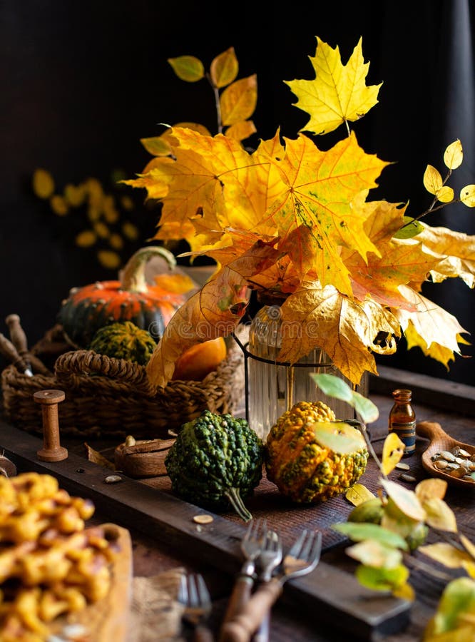Autumn still life with bouquet of fall leaves in glass vase on brown rustic table stock photo