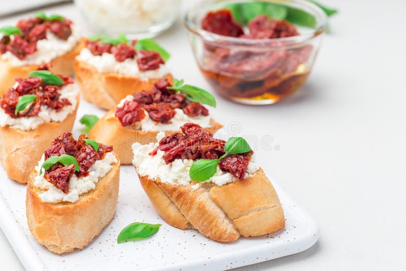 Bruschetta with sun dried tomato, feta and philadelphia cheese and basil on ceramic plate, horizontal, copy space. Bruschetta with sun dried tomato, feta and royalty free stock photos