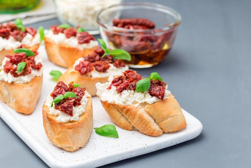 Bruschetta with sun dried tomato, feta and philadelphia cheese and basil on a ceramic plate, horizontal, copy space. Bruschetta with sun dried tomato, feta and royalty free stock photography