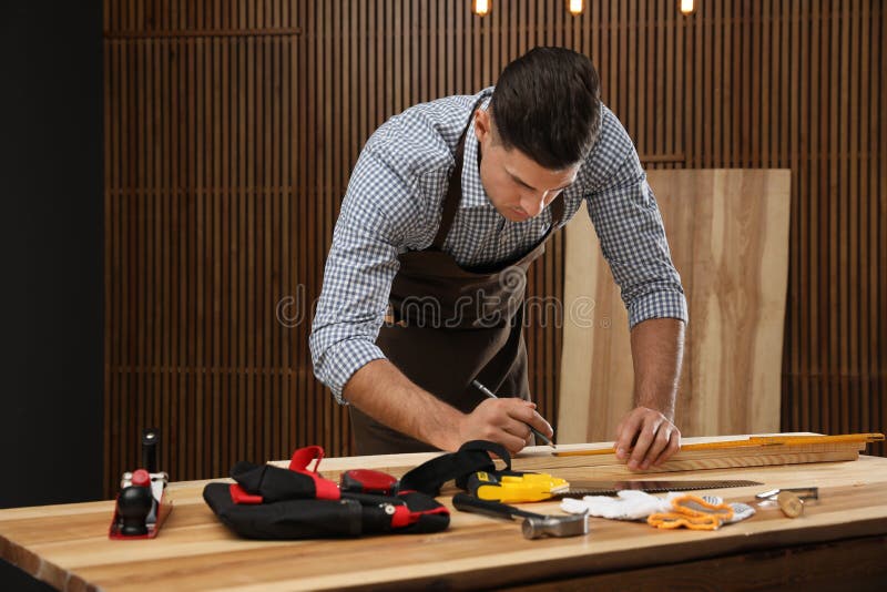 Carpenter marking length of wooden plank with pencil royalty free stock image