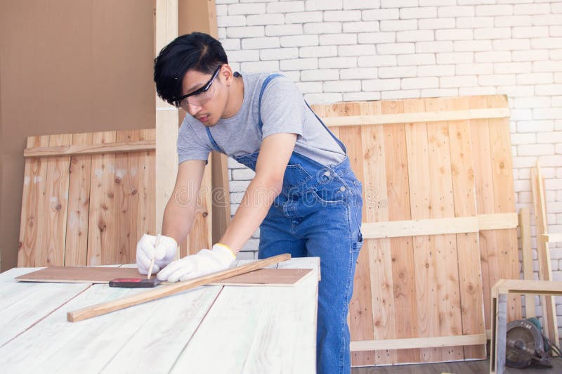 A carpenter is using pencil for marking on wood stock images