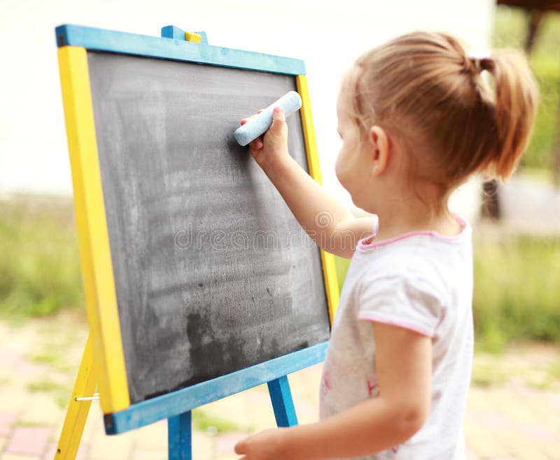 Child drawing. With chalk at the blackboard stock images
