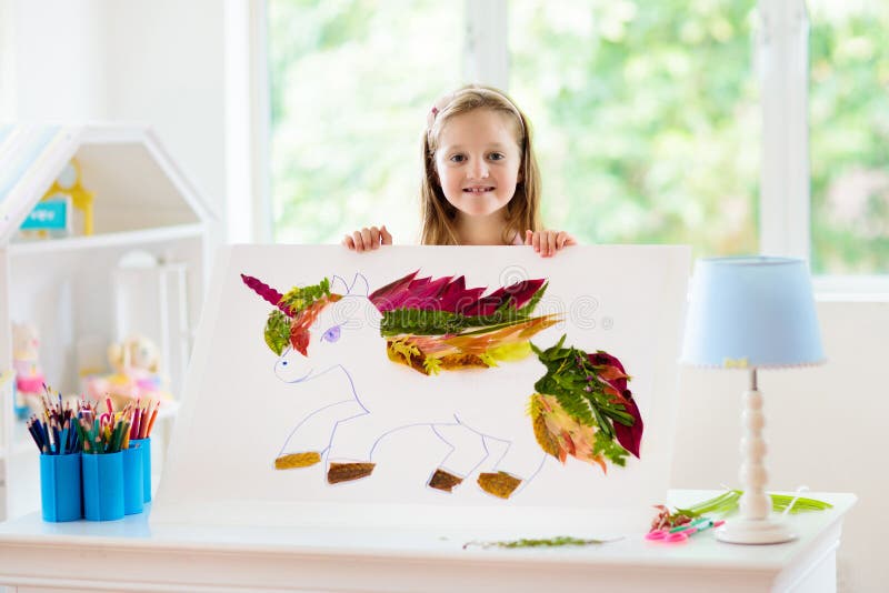 Child drawing unicorn using tree leaves. Kid painting pony or horse at home. Little girl doing homework after school. Kids crafts and art. Children paint. Arts royalty free stock photos