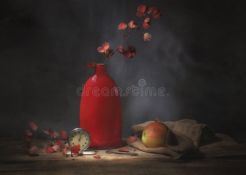 Classic still-life with a red vase, an apple, autumn leaves and  an alarm clock. Art photography. stock images