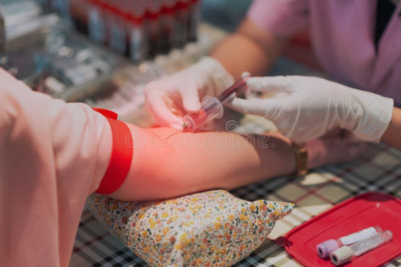 Close up nurse pricking needle syringe to vein patient drawing blood sample for blood test.  stock photography