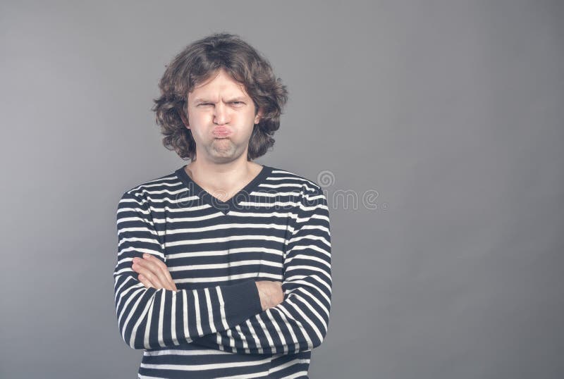 Funny comic man pouts lips and cheeks makes angry grimace, foolishes after all day working. Clueless male nerd with awkward. Expression has fun alone, plays royalty free stock photos