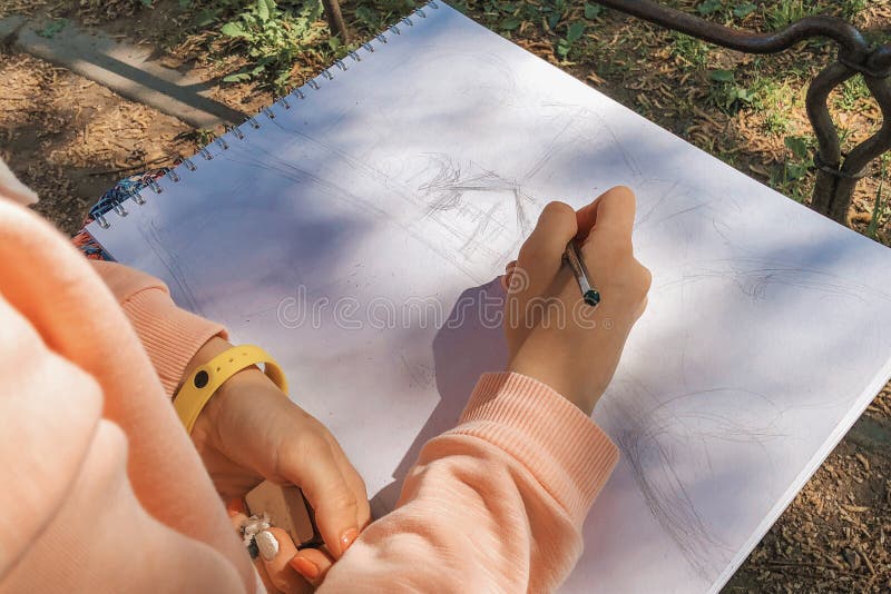 Girl drawing with black pencil a fantasy sketch in sketchbook. Plein Air in the park stock photos Girl drawing with black pencil a fantasy sketch in sketchbook. Plein Air in the park stock photos