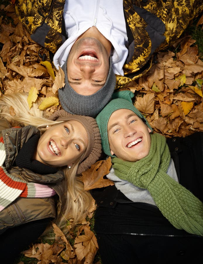 Happy people in autumn park laying among leaves stock image