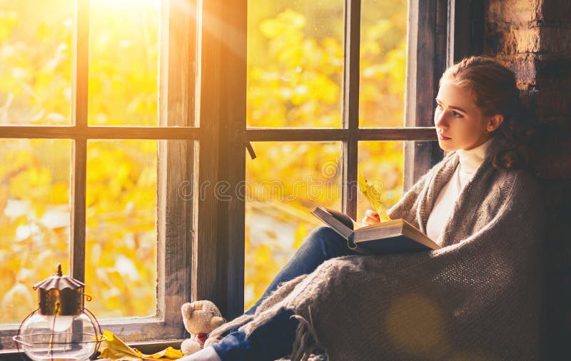 Happy woman reading book by autumn window stock image
