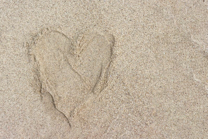 Heart shape by human foot print on sand beach. Background royalty free stock photography