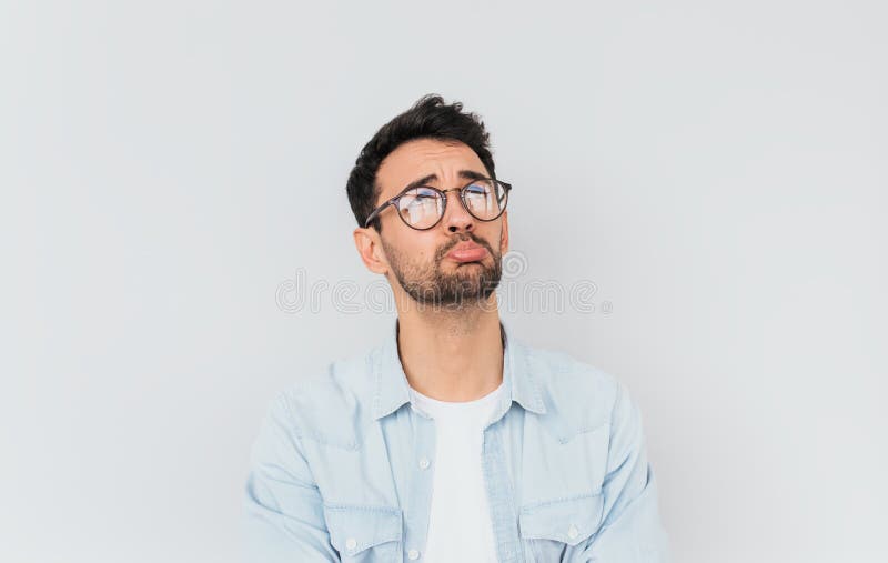 Horizontal portrait of stressed frustrated man curves lower lips isolated over white studio background. Bearded male having sad. Expression wearing blue shirt royalty free stock photos