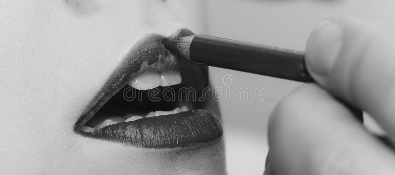 Lips getting red pencil makeup by male hand. Open mouth with white healthy teeth on female face. Young facial skin. Visage, make up and skincare. Beauty salon stock image