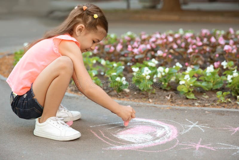 Little child drawing heart with chalk. On asphalt stock photos