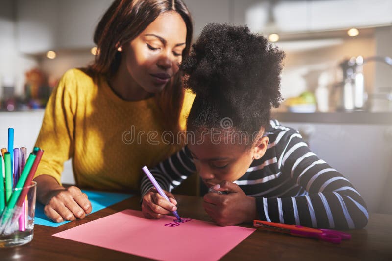 Mom and child drawing. In kitchen, black mother and daughter royalty free stock images