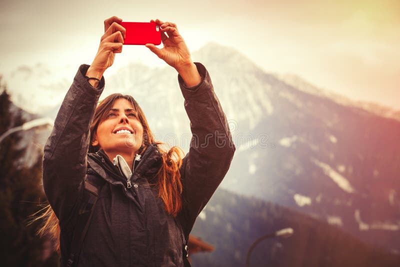 Mountain vacation. Happy woman taking a picture with a cell phone. stock images