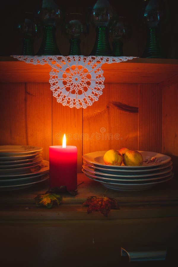 Old yellow painted cupboard with candles, a vase with red roses, autumn leaves and crocheted doilies stock photo