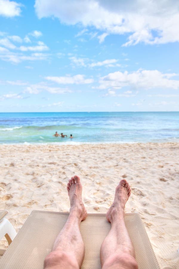 Personal perspective of man relaxing at beach with feet view. Personal perspective of man relaxing on a lounge chair at sandy beach with feet view towards sea stock photos Personal perspective of man relaxing at beach with feet view. Personal perspective of man relaxing on a lounge chair at sandy beach with feet view towards sea stock photos
