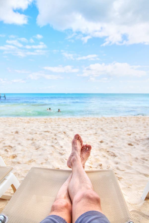 Personal perspective of man relaxing at beach with feet view. Personal perspective of man relaxing on a lounge chair at sandy beach with crossed legs view stock photos Personal perspective of man relaxing at beach with feet view. Personal perspective of man relaxing on a lounge chair at sandy beach with crossed legs view stock photos