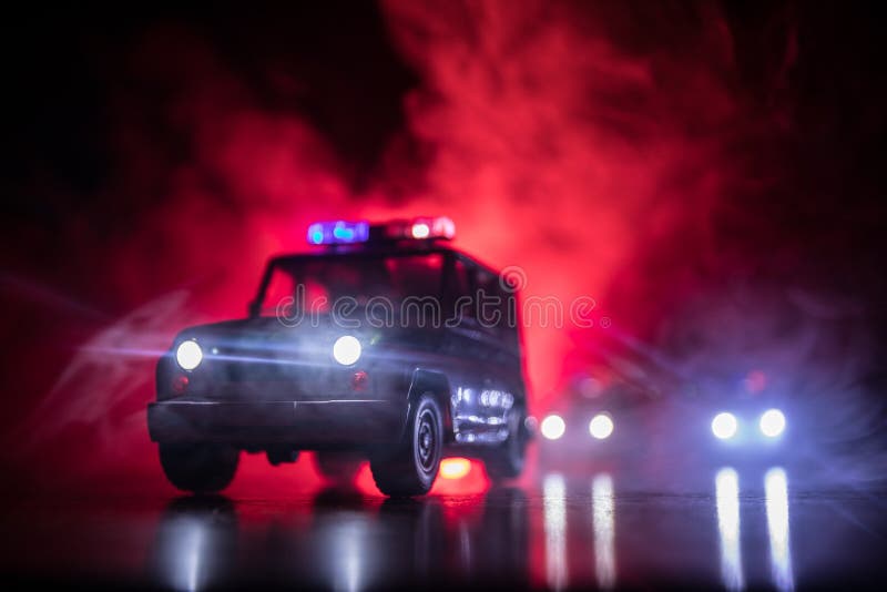 Police car chasing a car at night with fog background. 911 Emergency response police car speeding to scene of crime. Selective foc. Police cars at night. Police stock image Police car chasing a car at night with fog background. 911 Emergency response police car speeding to scene of crime. Selective foc. Police cars at night. Police stock image