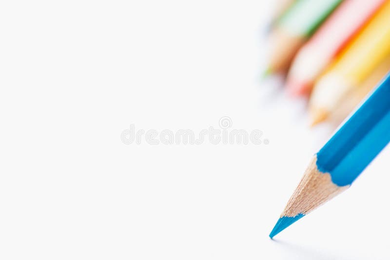 Row of Multicolored Pencils in Background Single Blue Sharp Pencil Pointing with Tip to Blank White Paper. Beginning of Drawing stock images