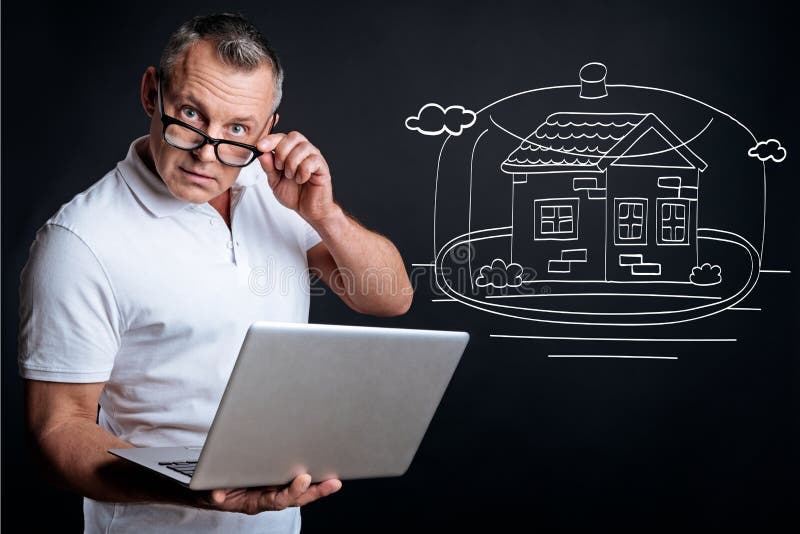 Serious man planning buying the house. Think it over in advance. Serious adult businessman holding laptop and looking at you while planning buying new house royalty free stock photos Serious man planning buying the house. Think it over in advance. Serious adult businessman holding laptop and looking at you while planning buying new house royalty free stock photos
