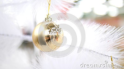 Close up, male lips blow on a golden ball on a white artificial christmas tree.  stock footage