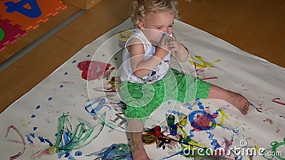 Happy baby girl painting her face with colorful fingers paint stock video footage