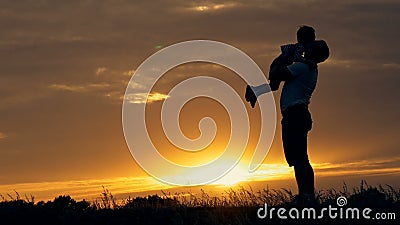 Silhouette of happy family father of mother and two sons playing outdoors in field at sunset stock video